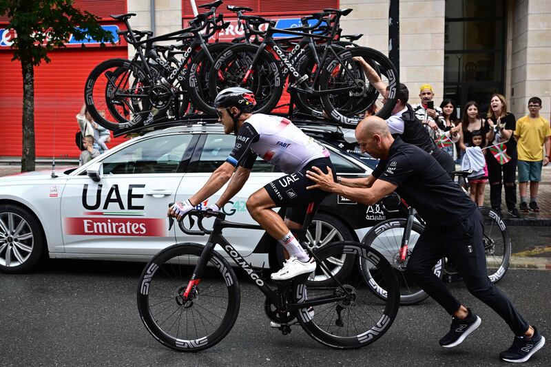 UAE Team Emirates rider Matteo Trentin is helped by a team member after suffering a fall. AFP