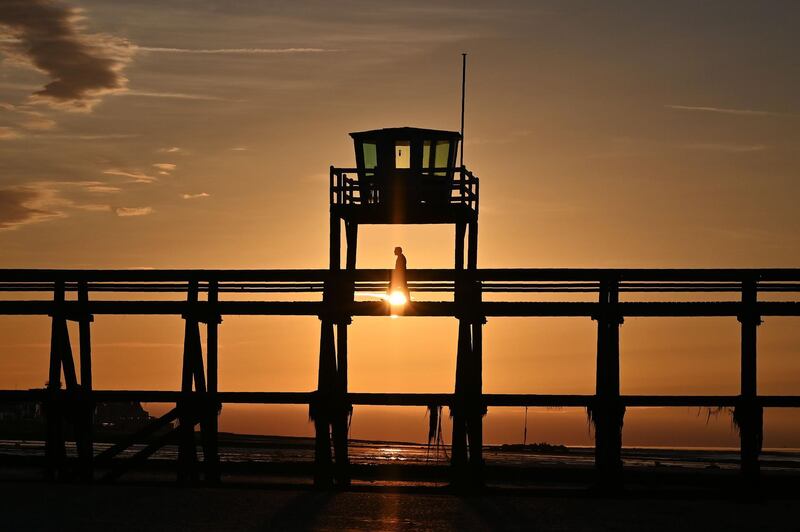 A man walks on the pier at sunset in Luc-sur-mer, France. AFP