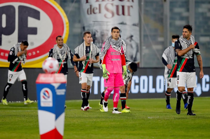 Club Deportivo Palestino players walk onto the pitch while wearing keffiyeh at the Monumental David Arellano Stadium, in Santiago. EPA