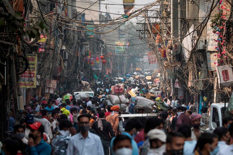 People walk along a street of a market area amid the Covid-19 coronavirus pandemic in New Delhi on November 7, 2020. / AFP / XAVIER GALIANA
