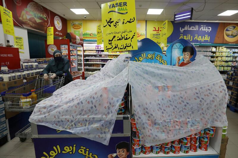 A woman shopping walks next to French products covered in protest of French cartoons of the Prophet Mohammad in Amman, Jordan. The cover reads in Arabic "In solidarity with the Prophet Mohammad peace be upon him, all French products have been boycotted". REUTERS