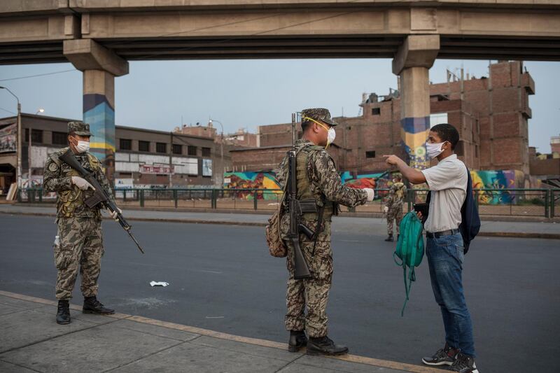 Soldiers check the personal documents of a man during the start of the curfew designed to slow the spread of the new coronavirus in Lima, Peru, Thursday, April 2, 2020. As the new coronavirus pandemic began hitting Peru, President Martin Vizcarra declared a state of emergency as deaths began to mount and ordered people to stay home. (AP Photo/Rodrigo Abd)