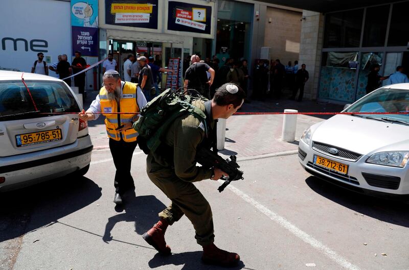 Israeli forensic police and soldiers inspect the place where an Israeli man was stabbed by a Palestinian near the entrance to a mall at the Gush Etzion junction, a settlement bloc next to the Palestinian town of Bethlehem in the occupied West Bank, on September 16, 2018.  / AFP / AHMAD GHARABLI
