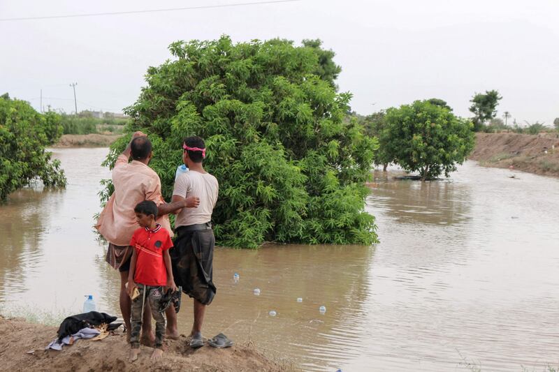 People stand by floodwater on July 25 after heavy rains in Yemen's Lahj Governorate.