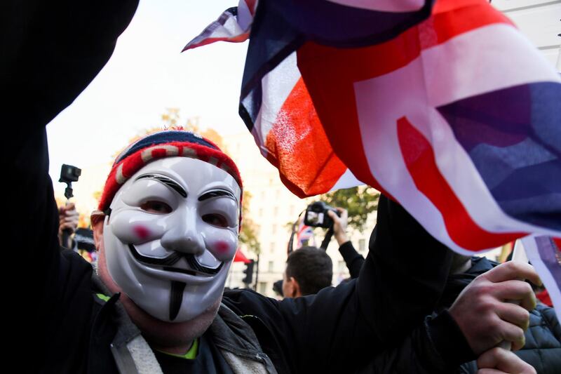 A Pro Brexit demonstrator wearing a Guy Fawkes mask, protests outside the gates of Downing Street in London, Thursday, Oct. 31, 2019. The EU has allowed Britain to delay its Brexit departure from the bloc until Jan. 31, enabling Britain to hold a general election on Dec. 12. (AP Photo/Alberto Pezzali)
