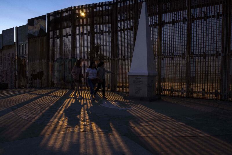 People walk along on the Mexican side of the U -Mexico border fence at Playas de Tijuana, northwestern Mexico. Guillermo Arias / AFP Photo