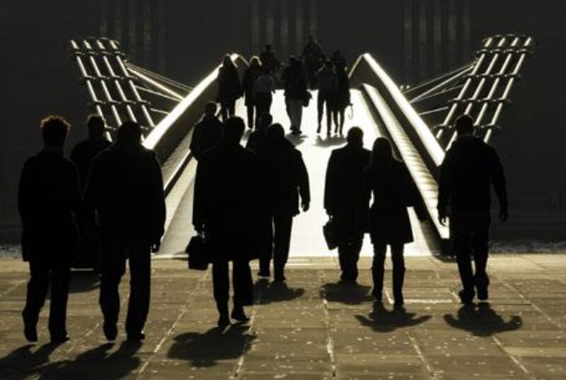 Pedestrians are silhouetted in the winter sun, as they walk onto the Millennium Bridge across the River Thames.