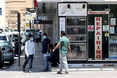 People wear protective face masks in Bur Dubai. Across the UAE, restrictions on movement will be stepped up to stem the spread of Covid-19. Pawan Singh / The National