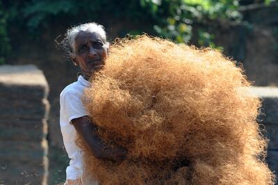 A Sri Lankan worker carries coconut-fibre in Piliyandala on the outskirts of Colombo. (Photo by LAKRUWAN WANNIARACHCHI / AFP)
