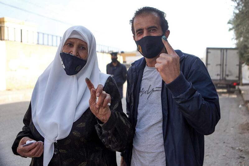 Voters, mask-clad due to Covid-19, show their ink-stained finger after voting in Jordan's northern Irbid. AFP