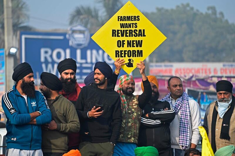 A farmer holds a placard during a nationwide general strike to protest against the recent agricultural reforms at the Delhi-Haryana state border in Singhu on December 8, 2020.  / AFP / Sajjad HUSSAIN
