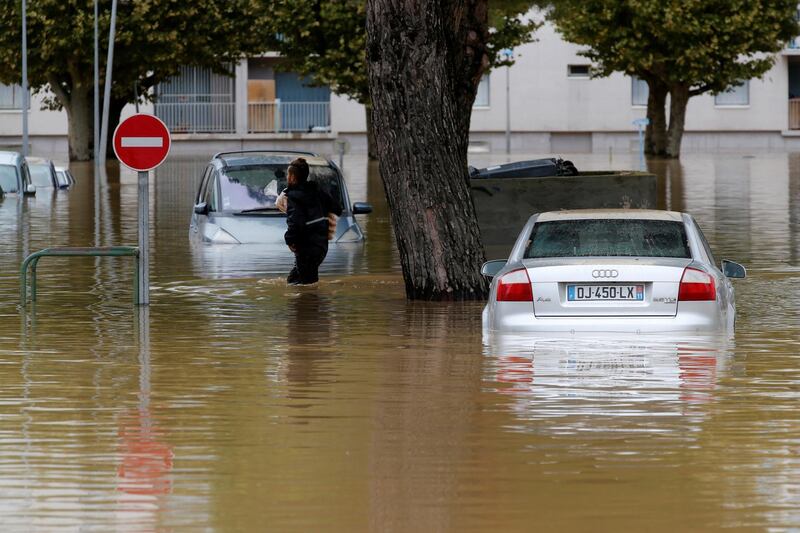 A man carries baguettes under his arm as he walks in high water. Reuters