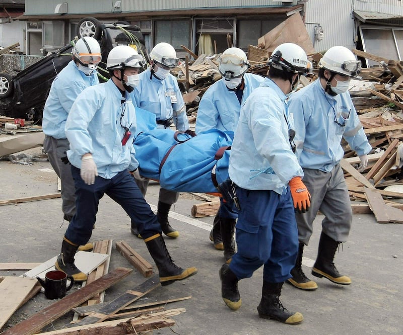 Rescue team members carry a dead body at Ofunato city in Iwate city on March 14, 2011. A new explosion at a nuclear plant hit punch-drunk Japan on March 14 as it raced to avert a reactor meltdown after a quake-tsunami disaster that is feared to have killed more than 10,000 people.   AFP PHOTO / JIJI PRESS
 *** Local Caption ***  524414-01-08.jpg