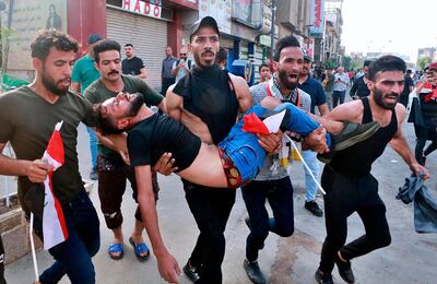 An injured protester is carried after reacting to tear gas fired by security forces during a protest in Tahrir Square, in central Baghdad, Iraq, Tuesday, Oct. 1, 2019. (AP Photo/Khalid Mohammed)