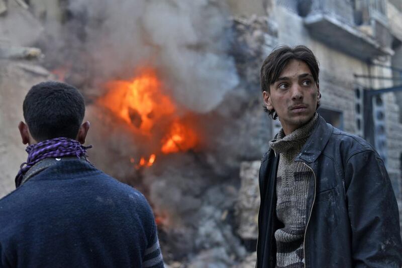 Civilians in Aleppo look on as a building erupts in flames after a government air strike. Unlike Russia, the West has no endgame in Syria. (EPA/Ali Mustafa)