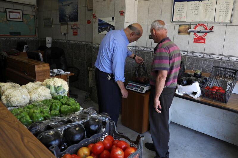 Mohammed Natour, who went from selling airline tickets to selling fruit and vegetables, after the coronavirus outbreak brought the tourism industry in Jordan to a sudden halt, serves a customer at his office in Amman, Jordan. Reuters