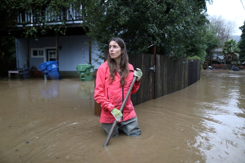 A woman clears debris and helps in her neighbourhood as the San Lorenzo River rises in Felton Grove. Reuters