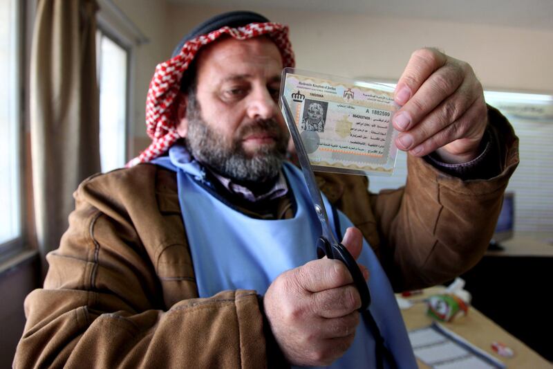 A Jordanian observer cuts the voter ID card of a woman after she cast her ballot at a polling station in Amman on January 23, 2013. Jordanians are voting in a parliamentary poll snubbed by Islamists who have staged strident pro-reform protests and who have already slammed what is expected to be an opposition-free body as illegitimate. AFP PHOTO/STR
 *** Local Caption ***  325414-01-08.jpg