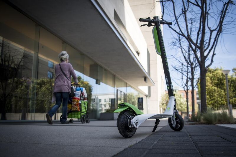 A pedestrian pushes a shopping cart past a Neutron Holdings Inc. LimeBike shared electric scooter in San Francisco, California, U.S., on Thursday, May 3, 2018. City officials, eager to do something about the electric scooters issue, are sending cease-and-desist letters and are planning to require permits soon, while impounding any that they say are parked illegally. Photographer: David Paul Morris/Bloomberg