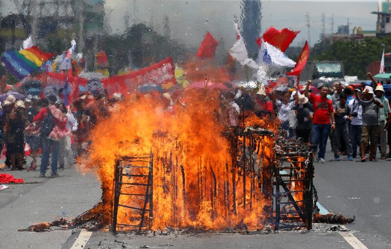 Anti-government protesters chant slogans in front of the remains of a burning effigy of a tank during a rally near the Philippine Congress. Erik De Castro / Reuters