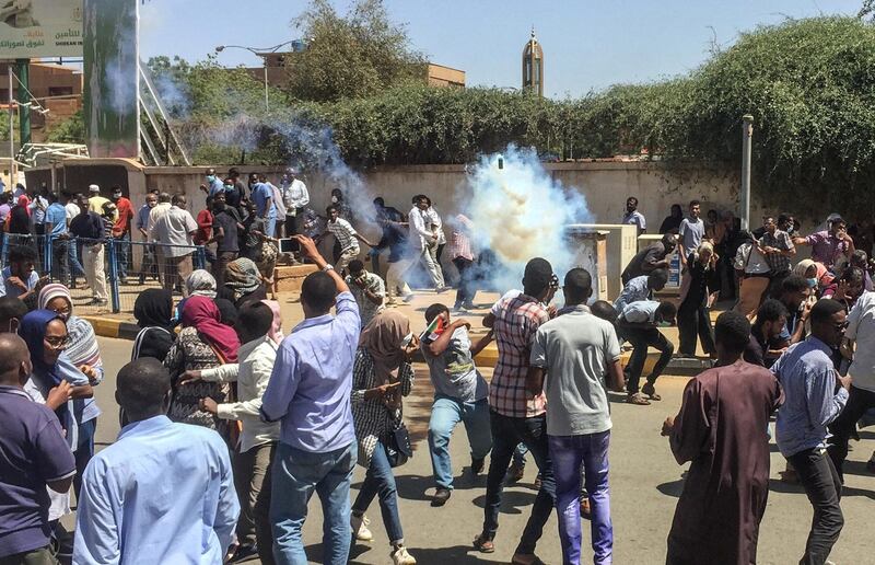 Sudanese protesters run for cover from tear gas canisters fired by police outside the military headquarters in the capital Khartoum on April 6, 2019. - Protests have rocked the east African country since December, with angry crowds accusing Bashir's government of mismanaging the economy that has led to soaring food prices and regular shortages of fuel and foreign currency. (Photo by - / AFP)