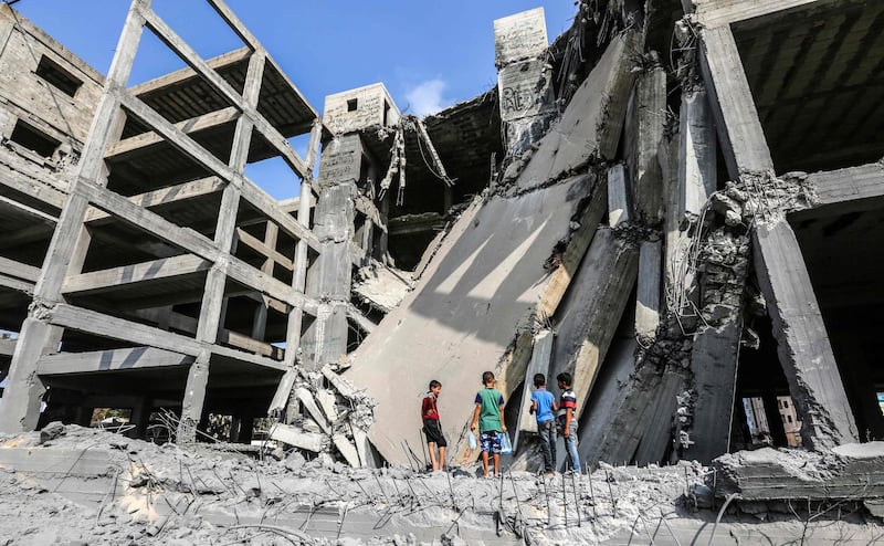 Palestinian boys walk through the wreckage of a building that was damaged by Israeli air strikes in Gaza City. AFP