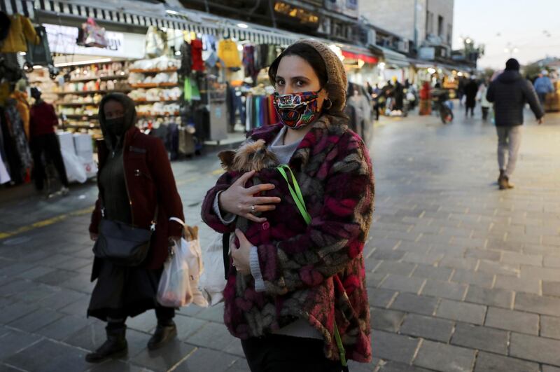 A woman holds a dog as she walks before Israel imposes a third national lockdown to fight climbing coronavirus disease (COVID-19) infections, in Jerusalem December 27, 2020. REUTERS/Ammar Awad