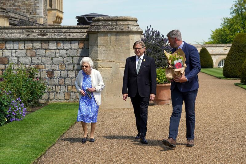 Queen Elizabeth II looks at flower beds after receiving a Duke of Edinburgh rose, given to her by Keith Weed, centre, president of the Royal Horticultural Society. AP