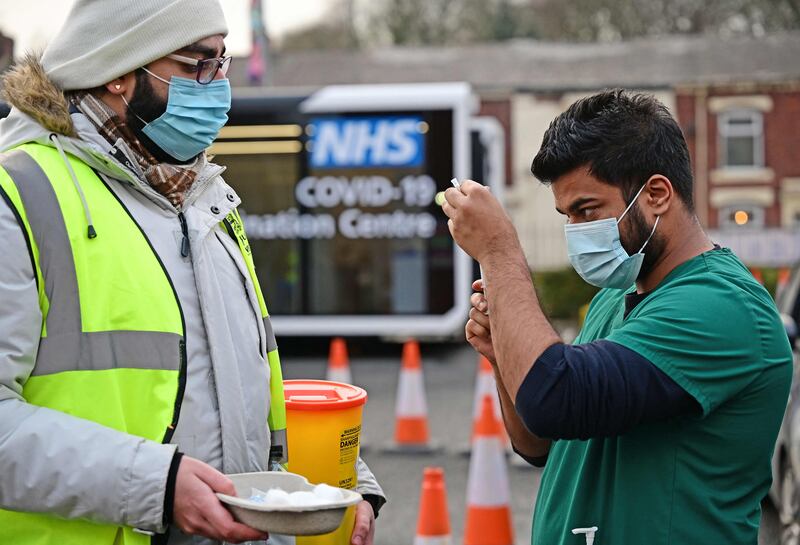 A health worker draws up a dose of a Covid-19 shot at a drive-through vaccination centre outside Ewood Park, Blackburn Rovers FC's ground, in north-west England. AFP