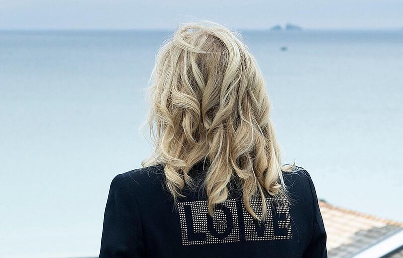 TOPSHOT - US First Lady Jill Biden, wearing a jacket with the words 'love' on the back, poses for a photograph looking out over the sea, at Carbis Bay, in Cornwall on June 10, 2021, ahead of the three-day G7 summit being held from 11-13 June.  G7 leaders from Canada, France, Germany, Italy, Japan, the UK and the United States meet this weekend for the first time in nearly two years, for the three-day talks in Carbis Bay, Cornwall. - 
 / AFP / Brendan Smialowski
