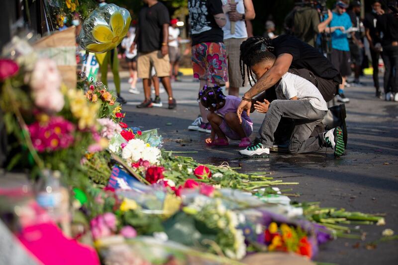 A man and two children mourn at the site of a Wendy's restaurant set ablaze overnight in Atlanta, Georgia. Rayshard Brooks, 27, was shot and killed on Friday by police in a struggle following a field sobriety test at the Wendy's.  Getty Images