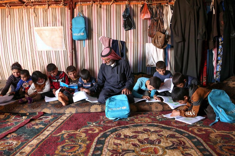Abderrazaq Khatoun helps his orphaned grandchildren with their school work. AFP