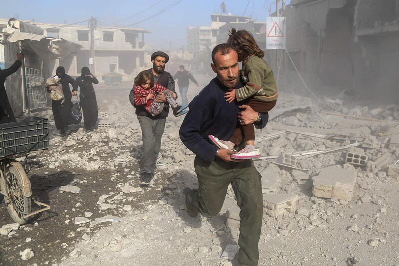 TOPSHOT - Syrians make their way through debris following a reported air strike in the rebel-held town of Beit Sawa, in the eastern Ghouta region on the outskirts of the capital Damascus, on December 3, 2017. / AFP PHOTO / Amer ALMOHIBANY