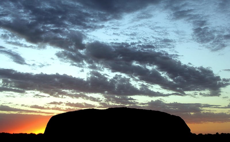 The sun rises at Uluru (Ayers Rock) in the World Hertage-listed Uluru-Kata Tjuta National Park, encompassing 1,325 square kms of desert in central Australia, 12 November 2005.  Uluru, the largest single rock in the world, is made of arkose (sandstone rich in feldspar) and soars 340 metres above the ochre plain.  AFP PHOTO/Torsten BLACKWOOD (Photo by TORSTEN BLACKWOOD / AFP)