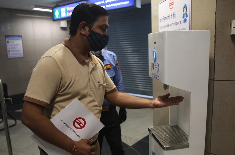 An Indian metro worker sanitises his hands from machine placed at the entrance of a metro station as a precautionary measure in New Delhi, India.  EPA