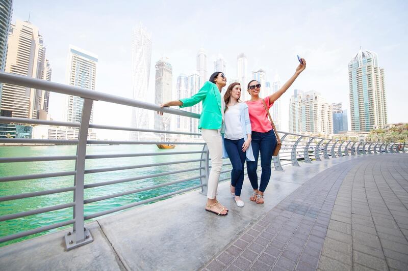 Young and beautiful women taking selfie against cityscape of Dubai Marina. Women is worn with casual clothes. Three women looks very happy. Skyscrapers in the background. Concept for urban lifestyle and friendship. Image is taken during Dubai Istockalypse in United Arab Emirates. Getty Images