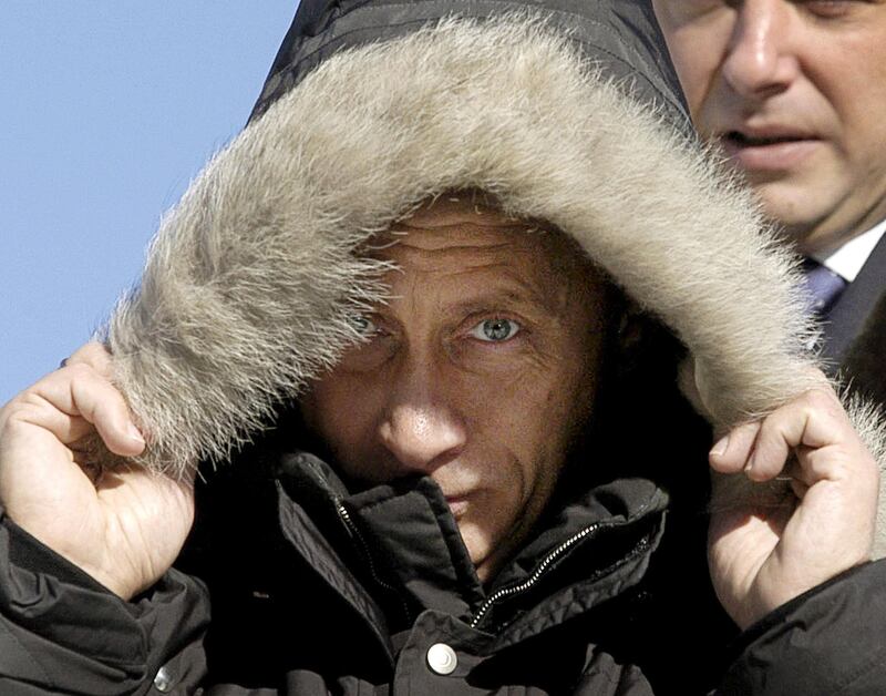 Putin warms himself during his visit to the native village of famous Russian writer Viktor Astafiev in Ovsianka on February 27, 2004. AFP