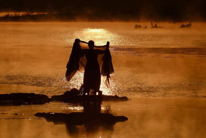 An Indian woman washes a sari in the Narmada River at sunrise on a foggy winter morning in Jabalpur. AFP