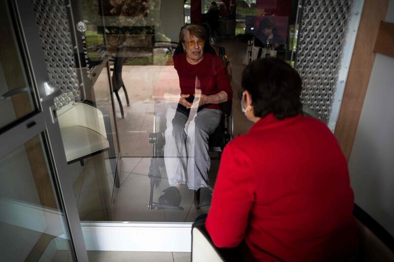 A woman speaks with her mother in a visiting room fitted with window during a visit in an accommodation facility for dependent elderly on April 21, 2020, in Toulouse, France. AFP