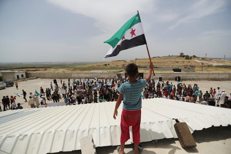 A boy holds the Free Syrian army flag during a protest calling for an end to the strikes and for Ankara to open the frontier at the Atmeh crossing on the Syrian-Turkish border, in Idlib governorate, Syria May 31, 2019. REUTERS/Khalil Ashawi