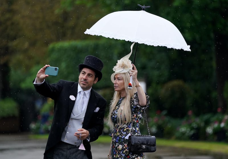Racegoers take cover from the heavy rain under an umbrella as they pose for a selfie during day four of Royal Ascot at Ascot Racecourse. Andrew Matthews/PA Wire