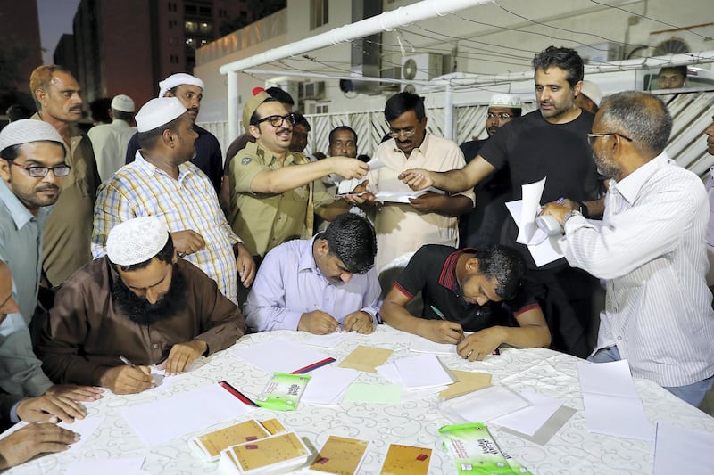 DUBAI , UNITED ARAB EMIRATES , JUNE 13 – 2018 :- Faraz Waqar ( postman ) member of the theatre group Goonj collecting letters from  labours during the iftar at Al Mehir Labour Camp in Al Quoz in Dubai. ( Pawan Singh / The National )  For News. Story by Anam Rizvi