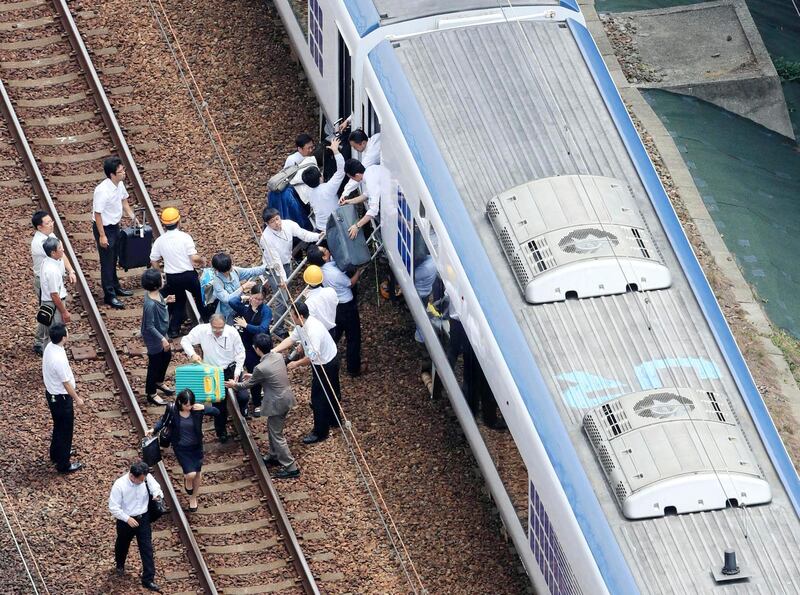 Passengers descend from a train on the track after train service was suspended to check for damage following an earthquake in Takatsuki city, Osaka. AP Photo