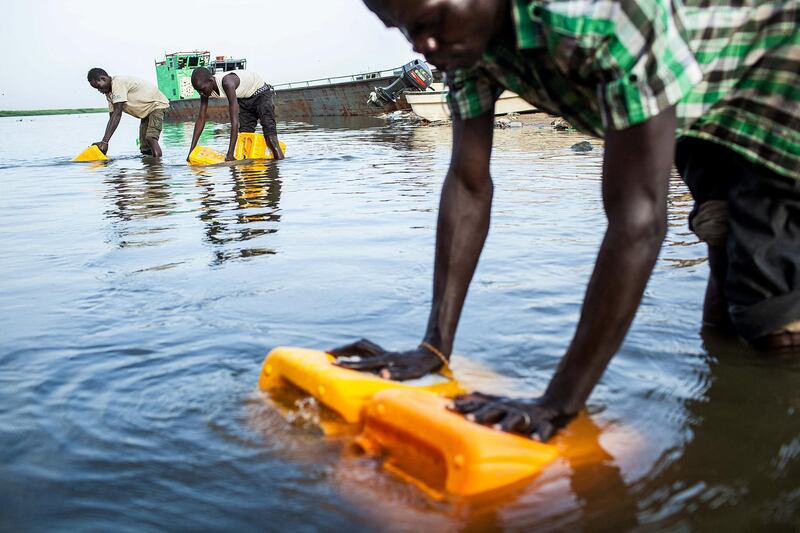 Young men load water from the river Nile into containers on February 26, 2014 in Bor, South Sudan. War crimes have been committed by all sides in conflict-wracked South Sudan, Human Rights Watch said on February 27 reporting widespread atrocities in weeks of carnage in the world's youngest nation. Thousands have been killed and almost 900,000 forced from their homes by over two months of battles between rebel and government forces, backed by troops from neighbouring Uganda.  AFP PHOTO / ANDREI PUNGOVSCHI (Photo by ANDREI PUNGOVSCHI / AFP)