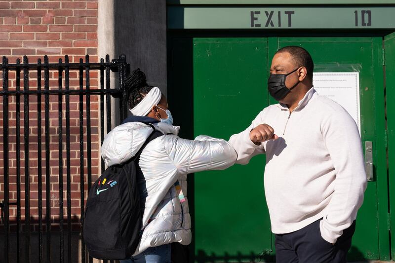 Linsey Johnson, right, a dean at Meyer Levin Middle School, greets a student, Thursday, Feb. 25, 2021, in New York. In-school learning resumed for middle school students in New York City for the first time since the fall of 2020. (AP Photo/Mark Lennihan)