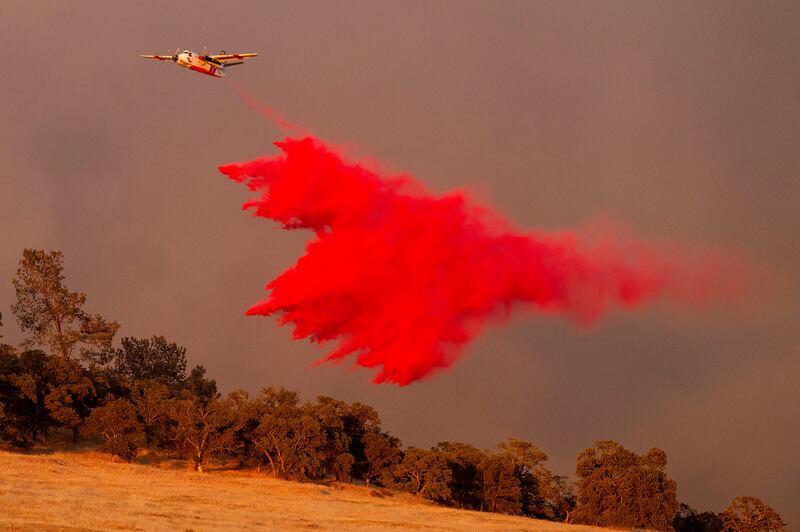A firefighting aircraft drops retardant while battling the Aero Fire, in the Copperopolis community of Calaveras County, California. AP