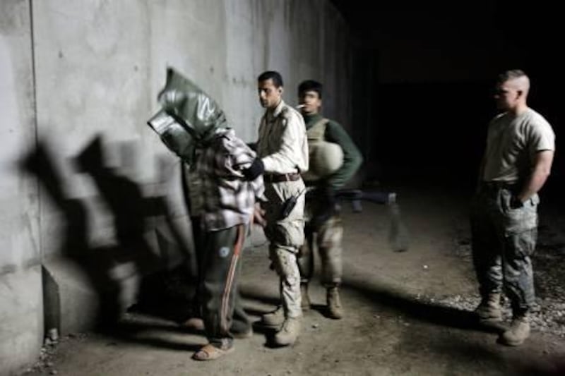 In this March 22, 2008 photo, a U.S. Army soldier, right, looks on as an Iraqi Army soldier escorting two hooded men detained in a raid by Iraqi troops in Mosul, Iraq. U.S. forces often failed to follow up on credible evidence that Iraqi forces mistreated, tortured and killed their captives in the battle against a violent insurgency, according to accounts contained in what was purportedly the largest leak of secret information in U.S. history. (AP Photo/Maya Alleruzzo) *** Local Caption ***  BAG108_Iraq_Wikileaks.jpg