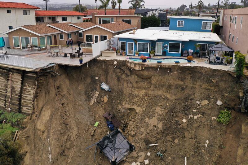 A swimming pool teeters on the brink after a landslide following torrential rain in Oceanside, California. AFP