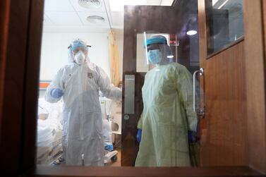 Chief medical officer Dr Adel Alsisi, left, and a colleague enter the room of a patient in the intensive care ward at Prime Hospital in Garhoud. Pawan Singh / The National