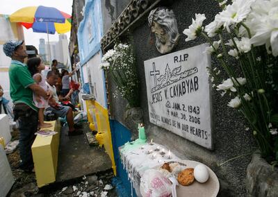 Food is offered to departed relatives as others pray while visiting at a public cemetery in Manila's Makati financial district  November 1, 2010. People flocked to cemeteries to spruce up the tombs of their loved ones for the annual celebration of All Saints Day, when millions of Filipinos remember their departed relatives and friends. REUTERS/Cheryl Ravelo (PHILIPPINES - Tags: SOCIETY RELIGION)
